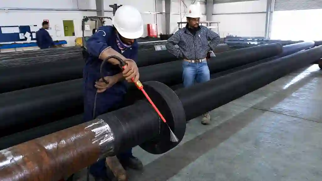 Worker performing holiday spark testing on rubber lined industrial pipeline in workshop